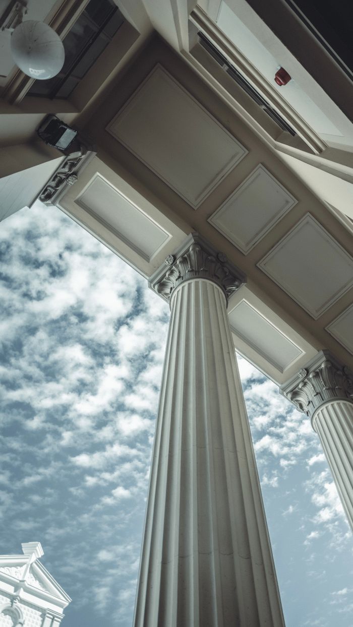 Low-angle view of architectural columns against a cloudy sky in Fremantle, Australia.