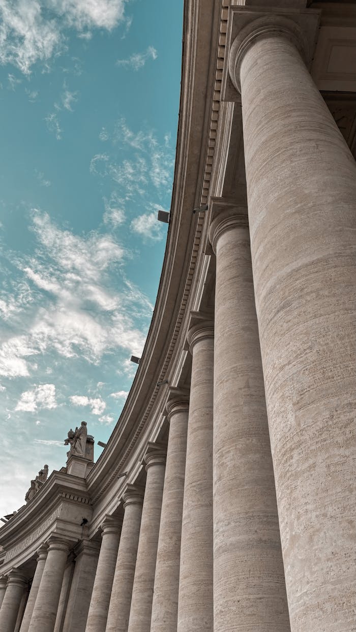 gallery-2 A striking image of classical architectural columns under a clear blue sky, showcasing grandeur and symmetry.