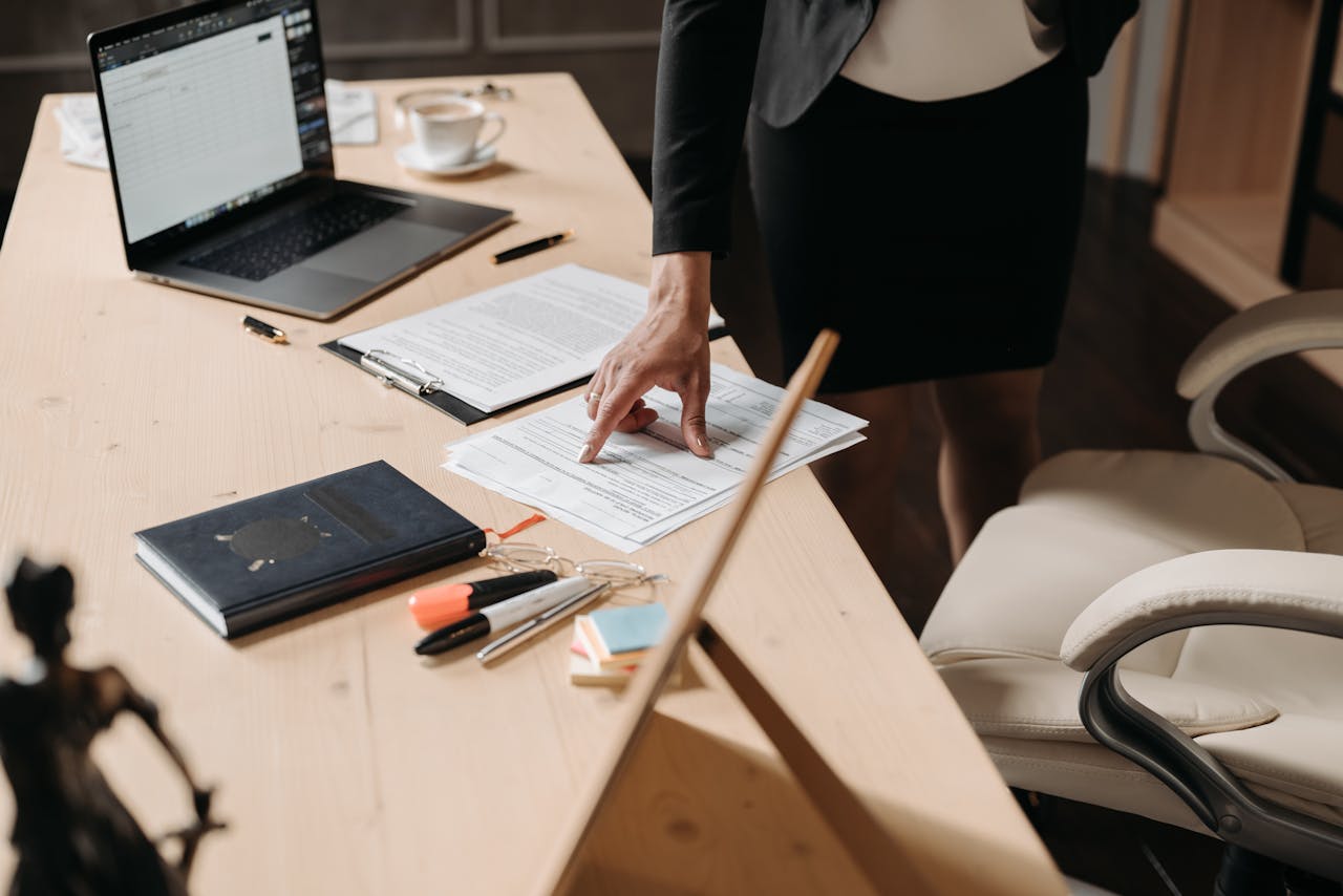 gallery-1 Businesswoman pointing at paperwork on a desk in an office setting, highlighting key data.